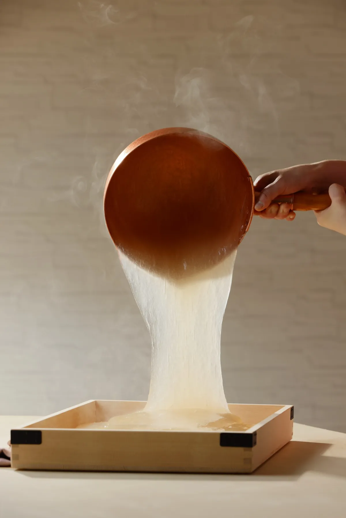 Freshly made warabimochi being poured into a wooden tray